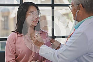 A young Asian female patient is being examined by a medical professional, A dignified middle-aged male doctor is diagnosing a