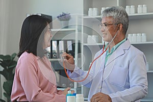 A young Asian female patient is being examined by a medical professional, A dignified middle-aged male doctor is diagnosing a