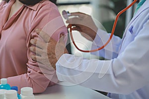 A young Asian female patient is being examined by a medical professional, A dignified middle-aged male doctor is diagnosing a