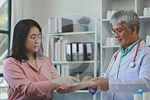 A young Asian female patient is being examined by a medical professional, A dignified middle-aged male doctor is diagnosing a