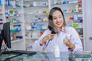 Young asian female pharmacist are scanning barcodes on white medicine bottles
