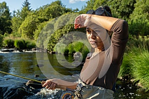 A young asian female standing fly fishing in a riffle on a river