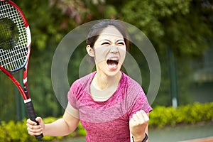 Young asian female tennis player celebrating after scoring