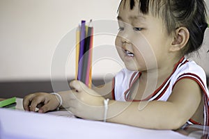 A young Asian female toddler with black hair is smiling.She happily with Colored pencils.And copy space