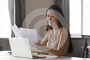 Young Asian female working with paper documents in office