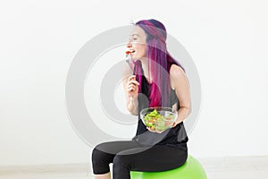 Young asian fitness girl eating a light vegetable salad after a workout at her home. Concept of losing weight and