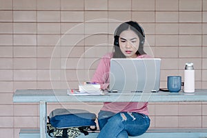 A young Asian freelance businesswoman working  on laptop at home during COVID-19  pandemic.. An adult learner studying online at