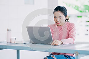 A young Asian freelance businesswoman working  on laptop at home during COVID-19  pandemic.. An adult learner studying online at