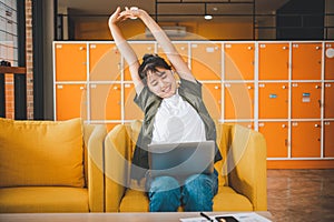 Young Asian freelancers are stretching oneself and relaxing after working and planning to work while working on laptop in the cafe photo