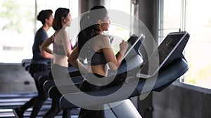 Young Asian friends run on treadmills in gym