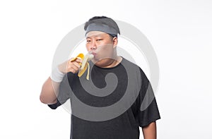 Young Asian funny fat sport man eating banana isolated on white background. Healthy lifestyle concept.