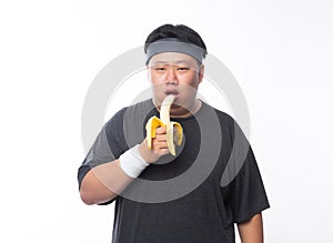 Young Asian funny fat sport man eating banana isolated on white background. Healthy lifestyle concept.