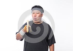 Young Asian funny fat sport man eating banana isolated on white background. Healthy lifestyle concept.