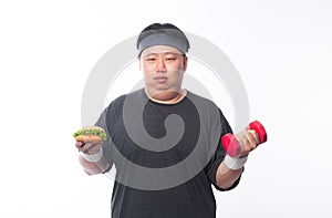 Young Asian funny fat sport man holding hamburger and dumbbell isolated on white background. Healthy lifestyle concept.