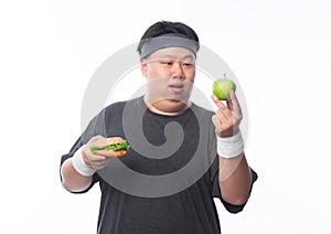 Young Asian funny fat sport man holding hamburger and green apple isolated on white background. Healthy lifestyle concept.