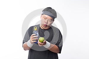 Young Asian funny fat sport man holding water bottle and green apple isolated on white background.