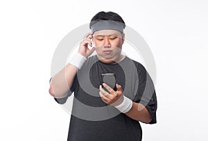 Young Asian funny fat sport man using smartphone listening music isolated on white background.