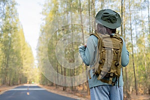 Young Asian girl with a backpack and hat hiking in the mountains during the summer season