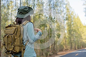 Young Asian girl with a backpack and hat hiking in the mountains during the summer season