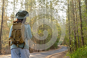 Young Asian girl with a backpack and hat hiking in the mountains during the summer season