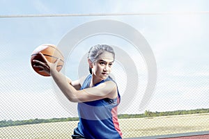 Young asian girl basketball player defending the ball from opponent on the outdoor basketball court
