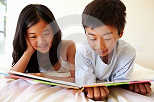 Young Asian girl and boy reading book