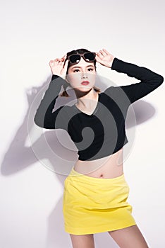 Young asian girl doing emotion. Dressed in a black shirt and yellow skirt, glasses and bright lips,trendy clothes.