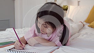 Young Asian girl drawing at home. Asia japanese woman child kid relax rest fun happy draw cartoon in sketchbook before sleep lying