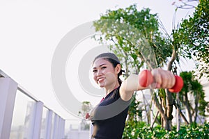 Young Asian girl excercising with dumbbell outdoor to saty fit