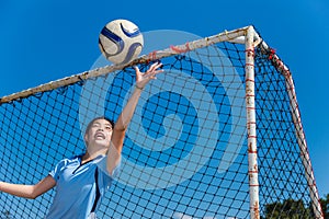 Young asian girl goalkeeper catching the ball