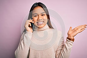 Young asian girl having conversation talking on the smartphone over isolated pink background very happy and excited, winner