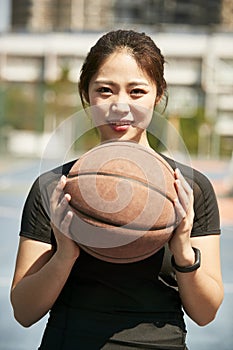 Young asian girl holding a basketball