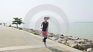 Young asian girl jogging by the sea