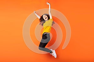 Young asian girl jumping up on orange background