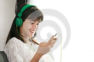 Young Asian girl listening to music with headphone and smarthphone