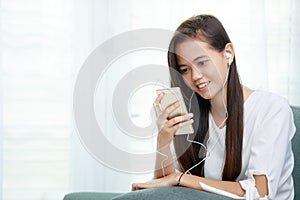 Young Asian girl listening to music with headphone and smarthphone