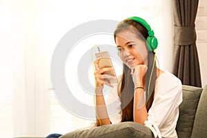 Young Asian girl listening to music with headphone and smarthphone