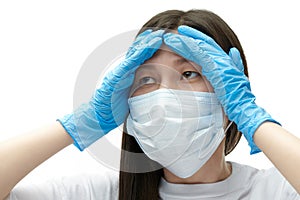 Young asian girl in medical mask and blue gloves in desperation holding her head