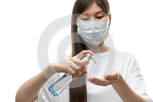 Young asian girl in medical mask using hand sanitizer