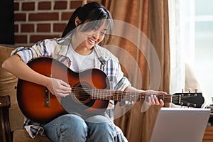 Young asian girl playing the guitar at home