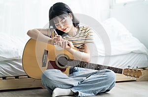 Young asian girl is practicing guitar at home and composing music