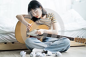 Young asian girl is practicing guitar at home and composing music