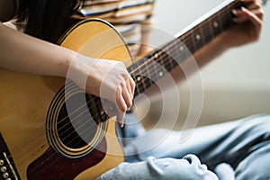 Young asian girl is practicing guitar at home and composing music