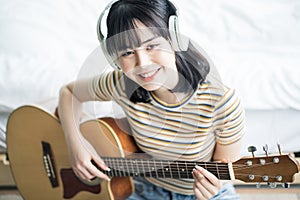 Young asian girl is practicing guitar at home and composing music