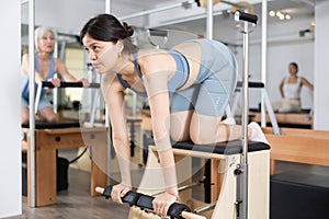 Young asian girl practicing pilates exercises on combo chair