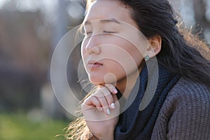 Young asian girl sitting in park with closed eyes and enjoying the moment.