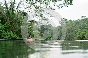 Young Asian Girl swimming in the infinity pool with beautiful view