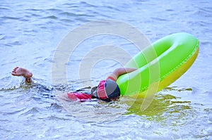 Young Asian girl swimming in ocean while looking underwater with her goggles.