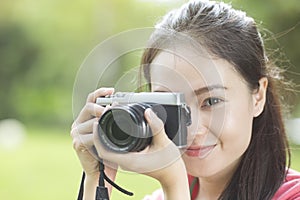 Young asian girl taking photo outdoors with digital camera