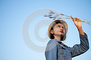 Young asian girl wear Jetket Jean hold grass flower .Blue sky background